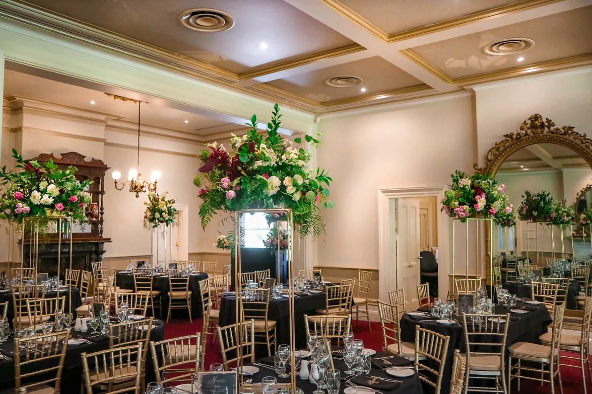 Grand cream-and-gold ballroom with gold-stand centrepieces and a gilt mirror